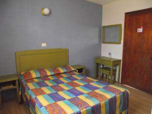 1 dormitorio con 1 cama con un edredón colorido en HOTEL POSADA SANTIAGO, en Xalapa