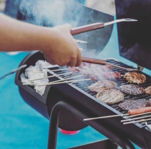 a person cooking food on a grill with tongs at Kembali Villas in Seminyak