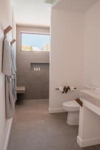 a white bathroom with a toilet and a window at The Mooring Resort in Panwa Beach