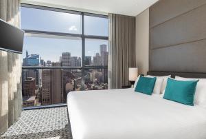 a bedroom with a large white bed and a large window at Fraser Suites Sydney in Sydney