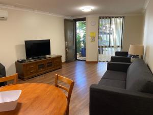 a living room with a couch and a tv and a table at Silver Sands Resort Mandurah in Mandurah