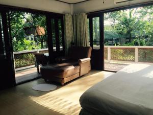 a bedroom with a bed and a chair and a window at Ruen Thai Rim Haad in Klaeng