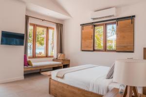 a bedroom with a bed and a couch and windows at The Mooring Resort in Panwa Beach