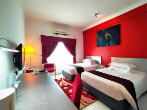 Habitación de hotel con 2 camas y pared roja en Klana Beach Resort Port Dickson, en Port Dickson
