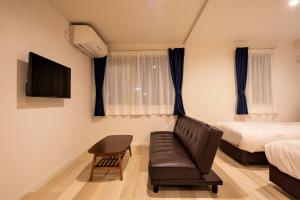 1 dormitorio con sofá, cama y TV en Cozy Inn OTARU en Otaru