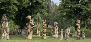 a group of wooden statues sitting in the grass at Art хостел-готель "Адреналін" in Luts'k