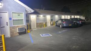 two cars parked in a parking lot in front of a house at La Perla motel in South Gate