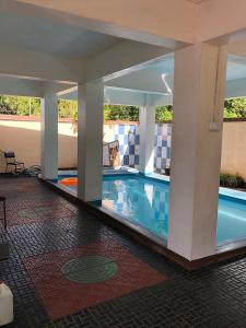 a swimming pool in a hotel with columns and a tile floor at Sunshine Villa in Grand-Baie