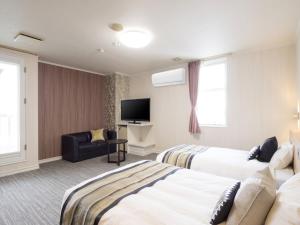 a hotel room with two beds and a flat screen tv at Hotel AreaOne Obihiro in Obihiro