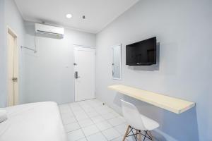a white room with a bed and a tv on the wall at Urban24 Syariah Depok in Depok