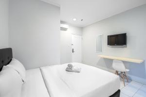 a white bedroom with a bed and a tv at Urban24 Syariah Depok in Depok