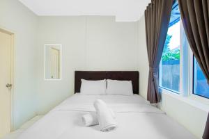 a white bedroom with a bed with a window at Urban24 Syariah Depok in Depok