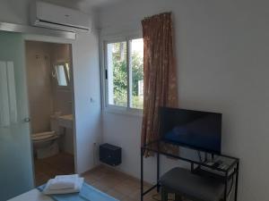 a living room with a television and a bathroom at Amistad in Paguera