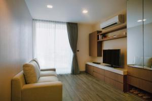 een woonkamer met een stoel en een televisie bij Olive Bangkok Hotel in Bangkok