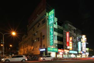 een straat met auto's die 's nachts voor gebouwen geparkeerd staan bij Tong Bing Express in Hsinchu City