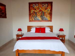 a bedroom with a bed with red pillows and a painting at Wonder Dive Bali Tulamben Villa's in Tulamben