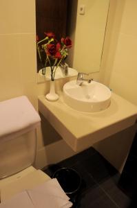 a bathroom with a sink and a vase with flowers on it at Amazing Beach Resort Palu in Palu