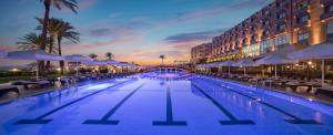 a large swimming pool with chairs and a building at Merit Park Hotel Casino & SPA in Kyrenia