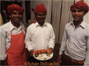 three men are holding a plate of food at KP Cottages in Kānker