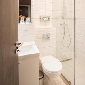a white bathroom with a toilet and a shower at Hotel Orion Várkert in Budapest
