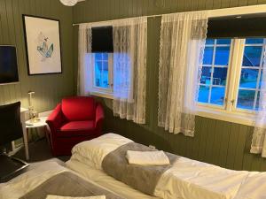 a bedroom with a bed and a red chair and windows at Bergtun Hotell in Valle