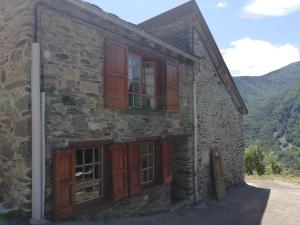 um antigo edifício de pedra com portas e janelas de madeira em Le Pijoulet em Tignac