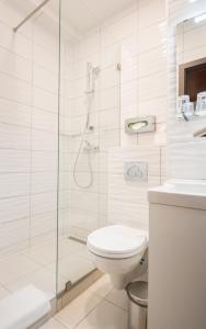 biała łazienka z prysznicem i toaletą w obiekcie Hotel Orion Várkert w Budapeszcie