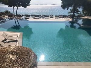 a swimming pool with chairs and the ocean in the background at Hotel King Saron Club Marmara in Isthmia