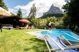 Ein Mann springt in ein Schwimmbad in der Unterkunft Haus Bergfrieden Seiser Alm Bahn in Seis am Schlern