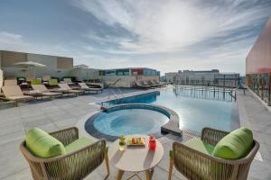 a pool on the roof of a hotel with chairs and a table at URBAN Al Khoory Hotel in Dubai