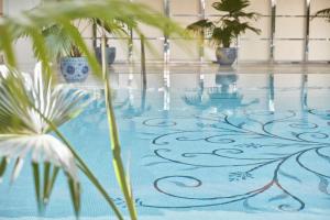 a swimming pool with palm trees and plants at The Peninsula Shanghai in Shanghai
