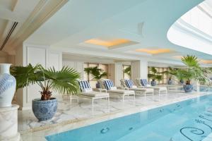 a pool in a hotel with chairs and plants at The Peninsula Shanghai in Shanghai