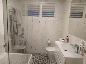 a bathroom with a shower and a toilet and a sink at Warilla Sands in Lake Illawarra