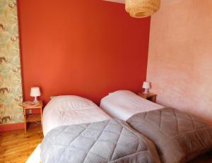dwa łóżka w pokoju z czerwoną ścianą w obiekcie l'heureux bazar w mieście Saint-Nectaire