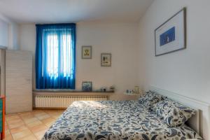 a bedroom with a bed and a window with blue curtains at La Cupolina Blu in Peretola