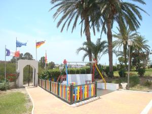 a playground in a park with palm trees and flags at Impressive in ground floor with terrace of 2 rooms and pool in Playas de Vera