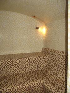 a bathroom with a bed in a tiled room at Nidos Poilsine Studio in Nida
