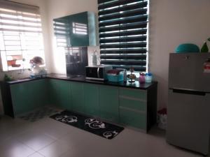 a kitchen with green cabinets and a refrigerator at Fathullah's Homestay in Alor Setar