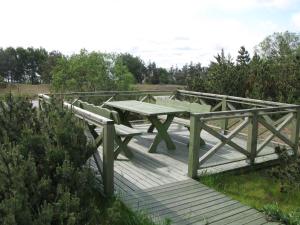 a picnic table and benches on a wooden deck at Nidos Poilsine Studio in Nida