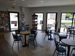a dining room with tables and chairs and windows at Do Mi Si La Do Ré gîte partagé in Saint-Carreuc