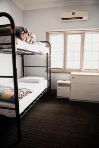 a room with two bunk beds with a person laying on them at The Emperors Crown Hostel in Perth
