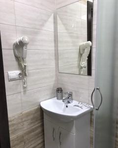 a white bathroom with a sink and a mirror at Gray Hotel in Vynohradiv