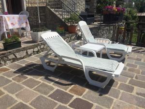 Dos sillas blancas sentadas en un patio de ladrillo en Casa Mary, en Brenzone sul Garda