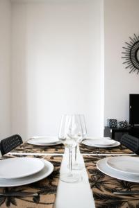 a table with white plates and a wine glass at Le Mille - Cosy appartement 4 personnes - 15mn du centre de Lyon in Villeurbanne