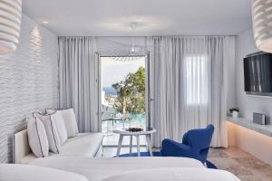 a bedroom with a couch and a table and a window at Myconian Ambassador Relais & Chateaux in Platis Gialos
