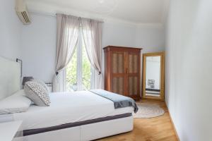 Habitación blanca con cama y espejo en Art House Station Rocafort ´Sant Antoni´, en Barcelona