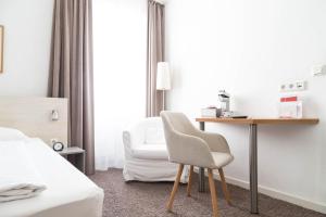 a hotel room with a desk and a chair at MAX Hotel Düsseldorf in Düsseldorf