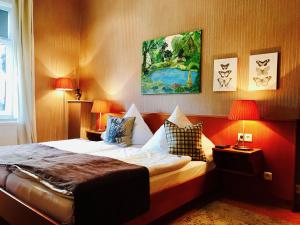 a bedroom with a bed with two lamps and a painting at ZU DEN LINDEN - RADEBEUL Pension mit Restaurant in Radebeul