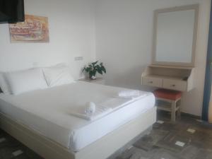 a white bed in a room with a table and a mirror at Frida Village in Hersonissos