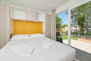 a bedroom with a white bed and a large window at Camping Ulika Mobile Homes - Naturist in Poreč +43 photos